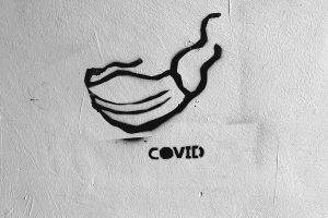 Graffiti von Maske mit Covid-Schriftzug